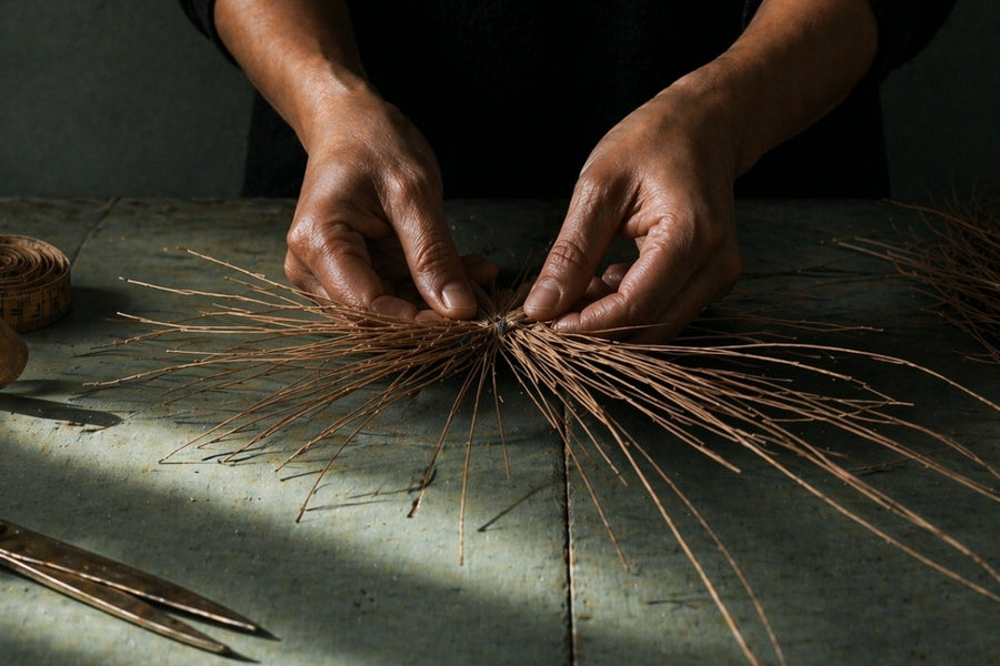 Hands weaving straw in artisan hat-making process on rustic table