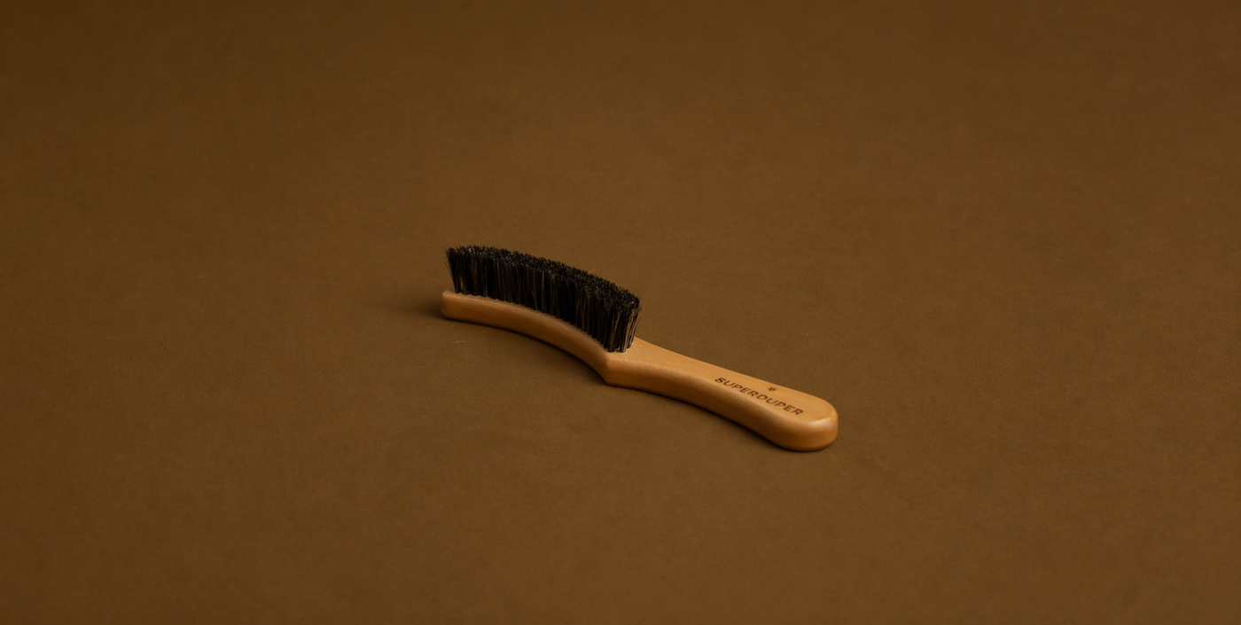 Curved wooden hat brush with black bristles on brown background for hat cleaning