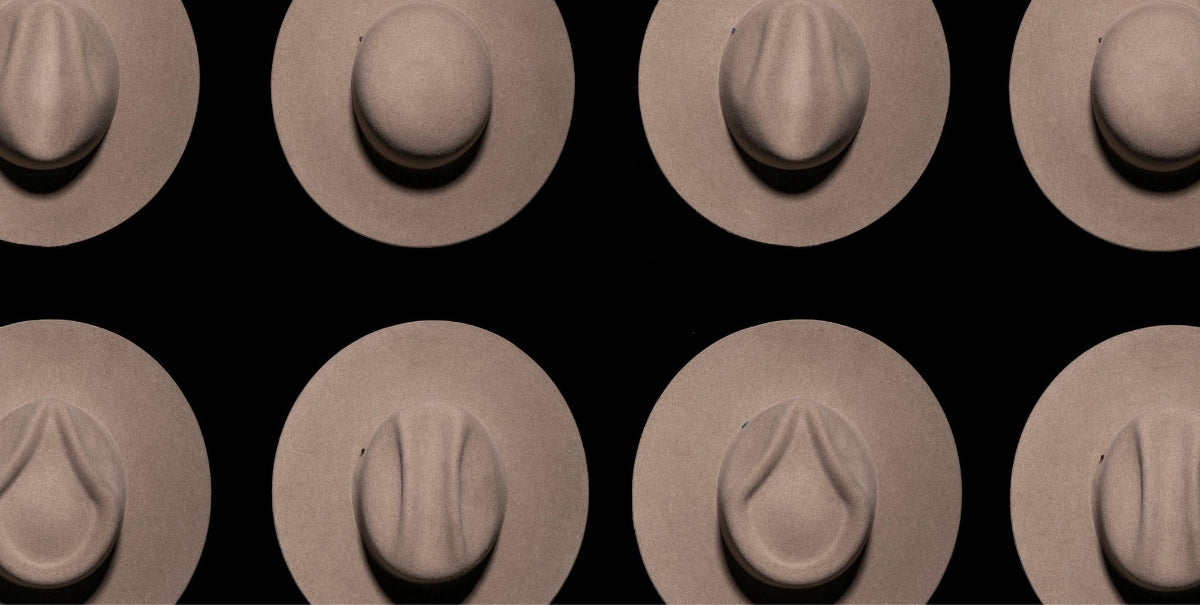 Various beige felt hats with different crown shapes on a black background