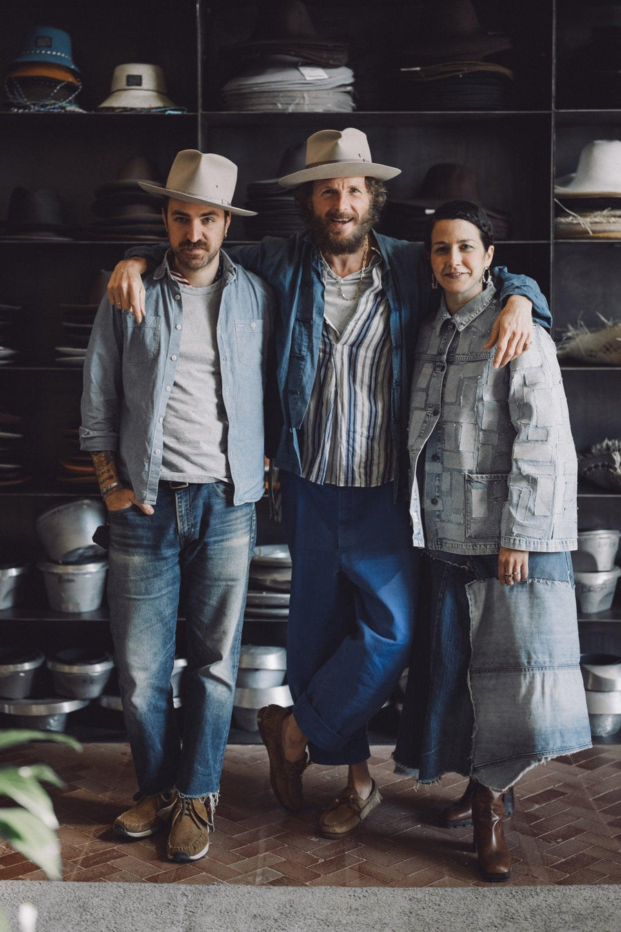 Three people wearing handmade felt hats and denim outfits in a hat store